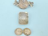 three pieces of silver and gold jewelry on a blue surface