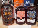 Plusieurs bouteilles d'alcool sont posées sur une étagère, accompagnées d'une étiquette de prix.