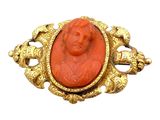 une image représentant une broche rouge et dorée sur laquelle figure le visage d'une femme