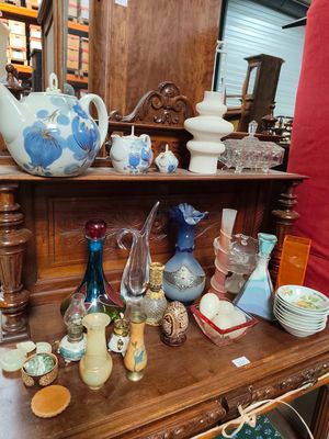 a wooden shelf with many different vases and dishes on it