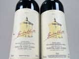 two bottles of red wine sitting next to each other on a table