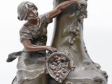 a bronze statue of a woman sitting on a vase