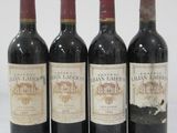 four bottles of wine are lined up in a row on a white surface