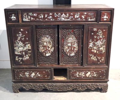 une armoire en bois comportant de nombreux tiroirs, sur laquelle est posé un vase