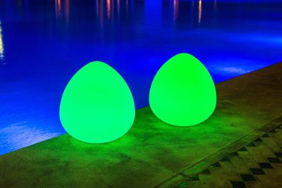 deux gros œufs verts posés près d'une piscine, la nuit