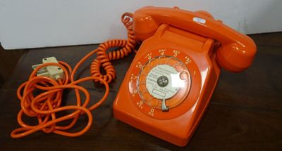 an orange telephone sitting on a table next to a charger