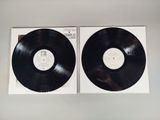 two black vinyl records sitting on top of each other on a white surface