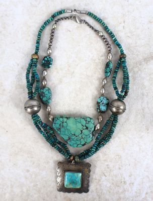 un gros plan d'un collier orné d'une pierre turquoise et de perles en argent