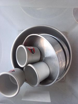 several cups are stacked in a metal bowl on a table