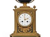 une horloge dorée et noire surmontée d'un bol noir