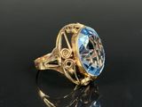 a close up of a gold ring with a blue topaz stone