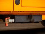 a close up of a yellow truck with a pipe attached to it ' s side