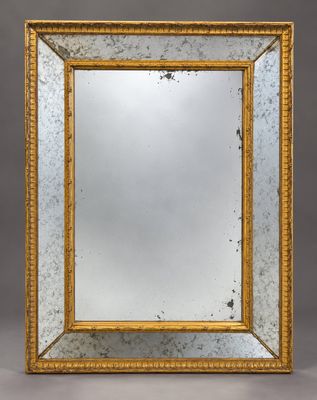 un miroir à cadre doré sur fond gris