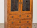 une vieille armoire en bois avec une porte vitrée, posée sur un parquet