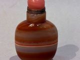 a small glass bottle with a pink top on a white surface
