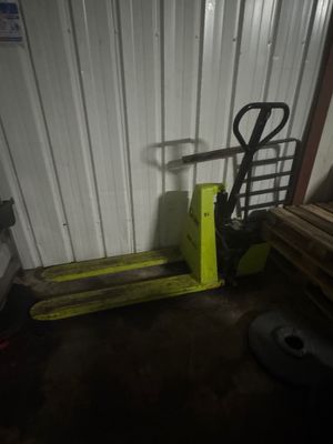 un chariot élévateur jaune garé à côté d'une pile de bois
