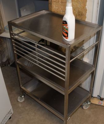 a metal cart with a bottle of cleaner on top of it