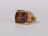 a close up of a gold ring with a purple stone