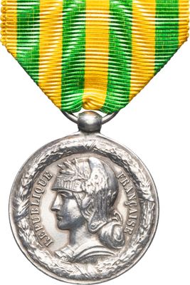 un gros plan d'une médaille sur fond blanc, ornée d'un ruban vert et jaune