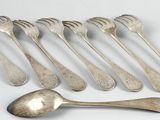 six spoons and a spoon rest on a white surface