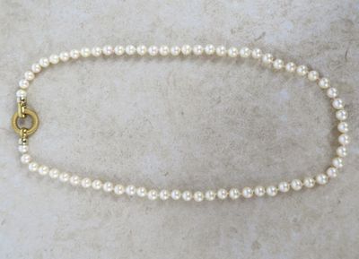 une photo d'un collier de perles blanches avec un fermoir en or