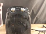 un petit radiateur soufflant posé sur une table à côté d'une paire de ciseaux