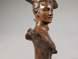 bronze bust of a woman with a hat on her head