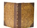 an old book with a brown cover sitting on top of a white surface