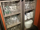bottles and glasses are stacked on top of each other in a cabinet