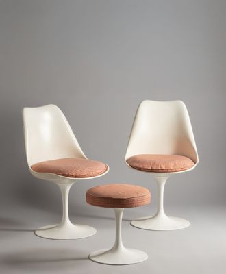 two white tulip chairs and a stool with a pink cushion