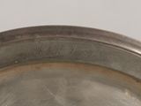 a silver plate with a silver handle on a table