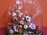 un dôme en verre contenant des fleurs, posé sur une table