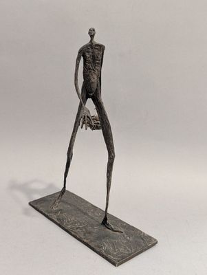 statue d'un homme tenant un livre, posée sur un socle, sur fond blanc