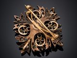 gold broochle with a bird on top of it on a black surface