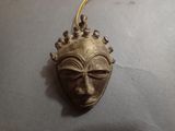 an image of a gold colored mask hanging from a gold chain