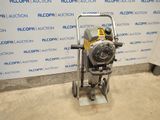 une machine argentée et jaune posée sur le sol, près d'un mur
