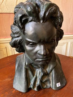 statue of a bust of a man with curly hair on a wooden table
