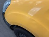 a close up of a yellow car with a denting on it