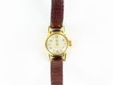 une image d'une montre en or avec un bracelet en cuir marron