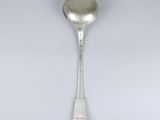 une cuillère ancienne en argent dont le manche repose sur une surface blanche