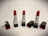 three red lipsticks are lined up on a white surface