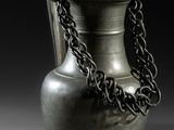 un vase en argent entouré d'une chaîne, posé sur une table