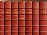 many red books lined up on a shelf in a library