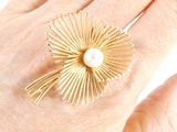 someone is holding a gold ring with a pearl in it