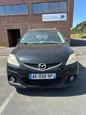 La voiture est garée devant l'immeuble, sur le parking.