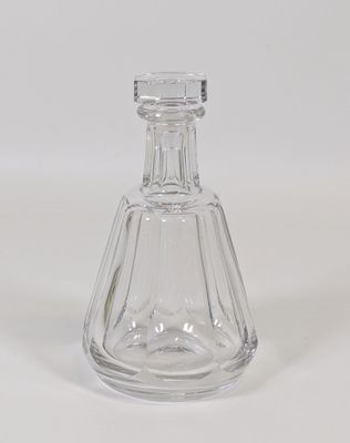une bouteille en verre transparent munie d'un bouchon, posée sur une surface blanche