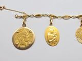 three gold coin necklaces hanging from a chain on a white surface
