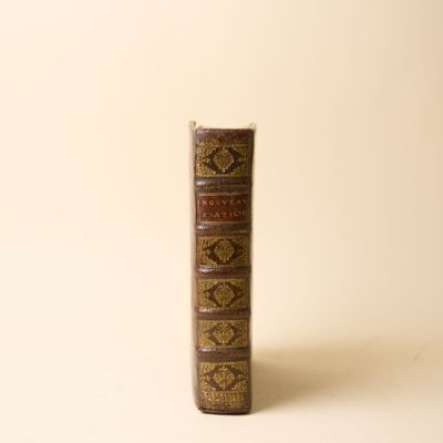 un vieux livre posé sur une table à côté d'un mur blanc