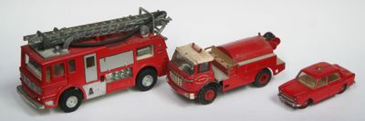 trois camions de pompiers miniatures et une voiture posés sur une surface blanche