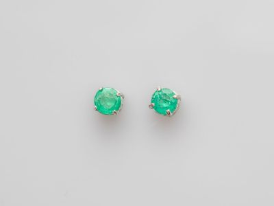 une paire de boucles d'oreilles en émeraude sur fond blanc